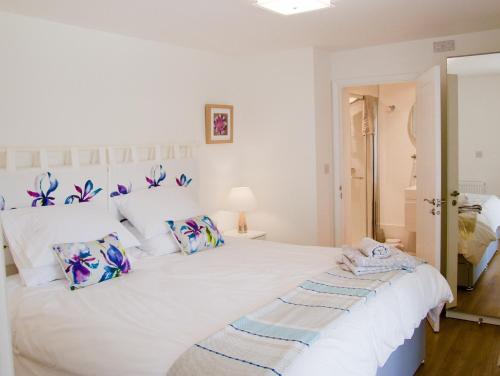 a white bedroom with a large white bed with pillows at Malvern Holiday- Garden Flat in Great Malvern
