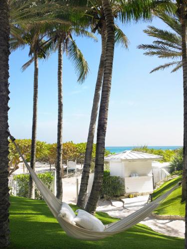 a hammock between palm trees at the beach at Grand Beach Hotel Surfside in Miami Beach