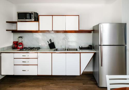 a kitchen with white cabinets and a stainless steel refrigerator at Puerto Plaza Las Terrenas in Las Terrenas