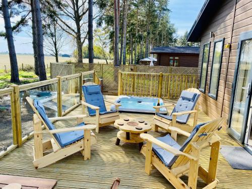 um deque com cadeiras de baloiço, uma mesa e uma piscina em Hollicarrs - Wildflower Lodge em York