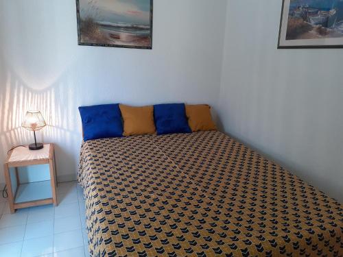 - un lit avec des oreillers bleus et jaunes dans l'établissement 3 Pièces terrasse vue MER et PISCINE Plage Richelieu CAP D'AGDE, au Cap d'Agde