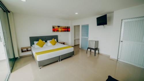 a bedroom with a bed with yellow pillows and a television at Green Coveñas by Bernalo Hotels in Coveñas