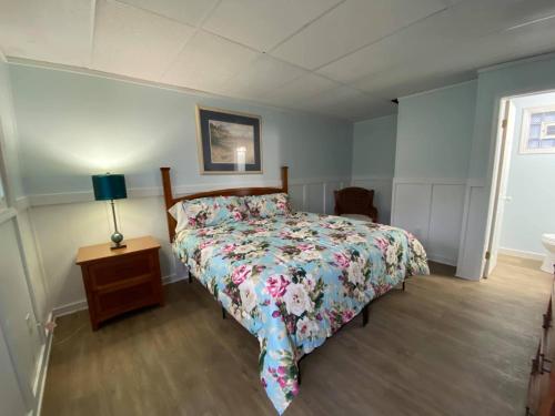 ein Schlafzimmer mit einem Bett und einem Tisch mit einer Lampe in der Unterkunft The Palms Motel in Geneva-on-the-Lake