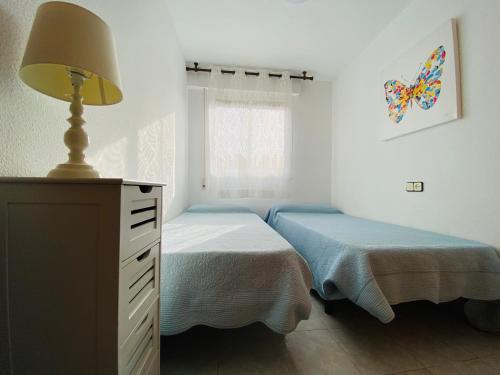 a bedroom with two beds and a lamp and a dresser at Terrazas Altamar in Alcossebre
