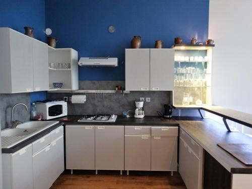 une cuisine avec des armoires blanches et un mur bleu dans l'établissement Location courte durée, à Saumur