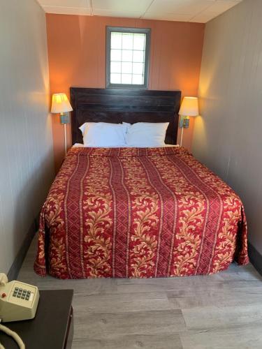 a bedroom with a bed with a red comforter and a telephone at Stadium View Inn in Hamburg