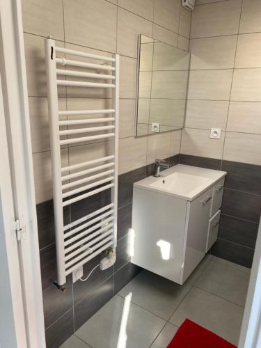 une salle de bain avec un lavabo blanc et un miroir dans l'établissement Au Rythme des Vagues, à Saint-Aubin-sur-Mer