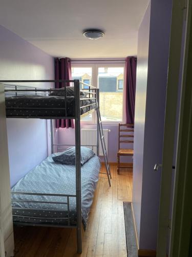 une chambre avec deux lits superposés et une fenêtre dans l'établissement Au Rythme des Vagues, à Saint-Aubin-sur-Mer