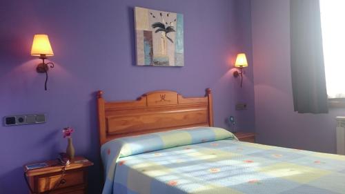a bedroom with a bed with purple walls and two lamps at Hotel Virginia R.H. in Vinuesa