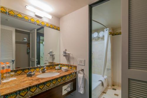 a bathroom with a sink and a shower and a mirror at Hotel Lucerna Culiacan in Culiacán