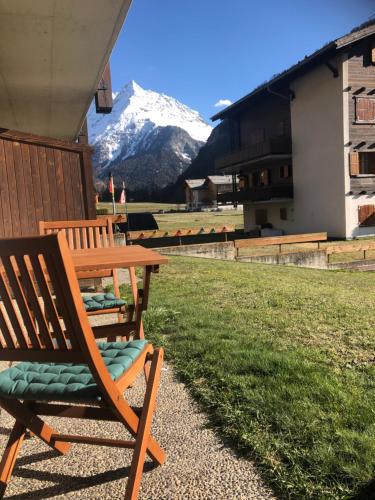 a wooden table and chair with a snow covered mountain at Le Cerf, magnifique studio avec jardin-terrasse et garage in Evolène