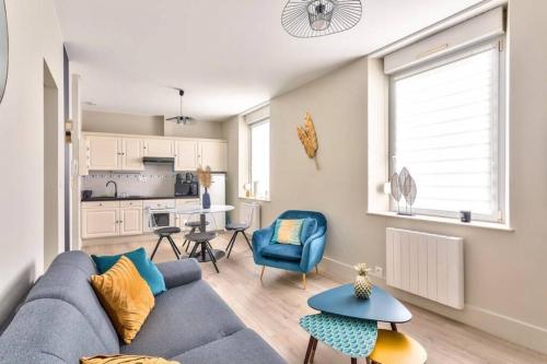 un salon avec un canapé bleu et une cuisine dans l'établissement LA PALME 50 m de la plage en baie de Somme, à Cayeux-sur-Mer