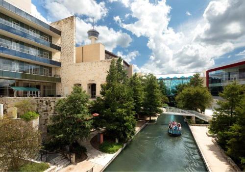 a boat on a river in front of a building at Grand Hyatt San Antonio River Walk in San Antonio