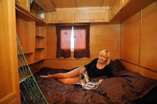 a woman sitting on a bed in a room at HOUSEBOAT Mazury Frajda in Giżycko