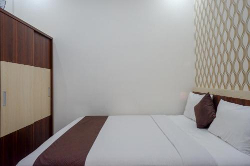a bedroom with a white bed with a wooden headboard at RedDoorz Syariah at Omah Sawah in Balong