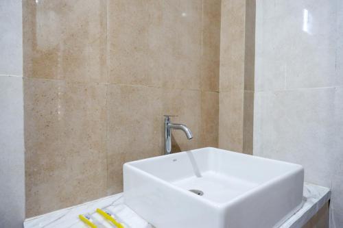 a white sink in a bathroom with a tiled wall at RedDoorz Syariah at Omah Sawah in Balong