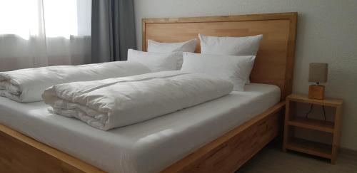 a large bed with white sheets and pillows at HB 32 Metzingen in Metzingen