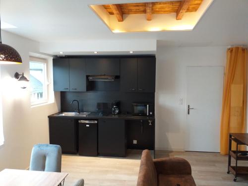 une cuisine avec des armoires noires et une table dans l'établissement Les Volets Bleus - Deux appartements et un studio, Jardin, à Bourges