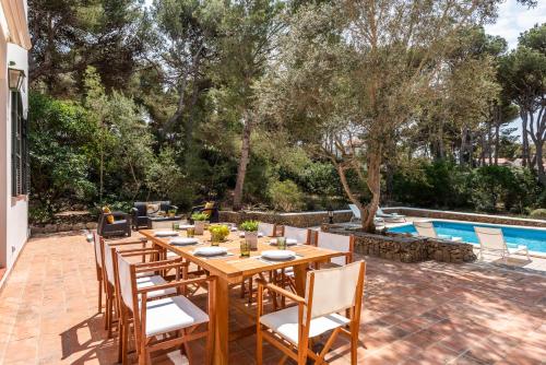 a wooden table and chairs on a patio with a pool at Villa Los Dragones in Son Parc