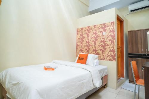 a bedroom with a white bed with an orange pillow at KoolKost Syariah at Ir Soekarno Solo Baru in Solo