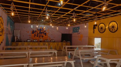 a restaurant with white tables and a yellow wall at Camp O Royale in Dhanaulti