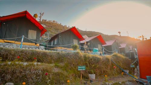 a row of houses with a rainbow in the background at Camp O Royale in Dhanaulti