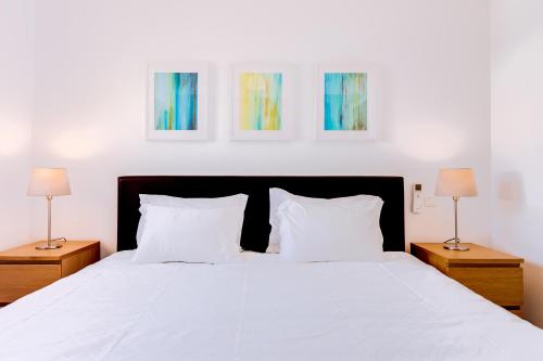 a bedroom with a white bed with two lamps at AL- Apartamentos Novos Vista Mar in Quarteira
