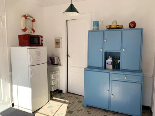 d'un meuble bleu dans la cuisine équipée d'un réfrigérateur. dans l'établissement Maison charmante Soulac-sur-Mer Jardin, à Soulac-sur-Mer
