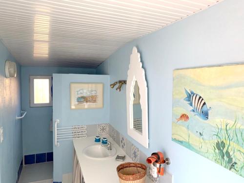 La salle de bains est pourvue de murs bleus et d'un lavabo. dans l'établissement Maison charmante Soulac-sur-Mer Jardin, à Soulac-sur-Mer