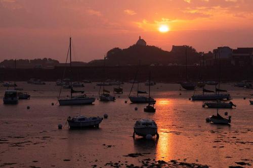 a group of boats in the water at sunset at Maison près de la plage et de la thalasso in Roscoff