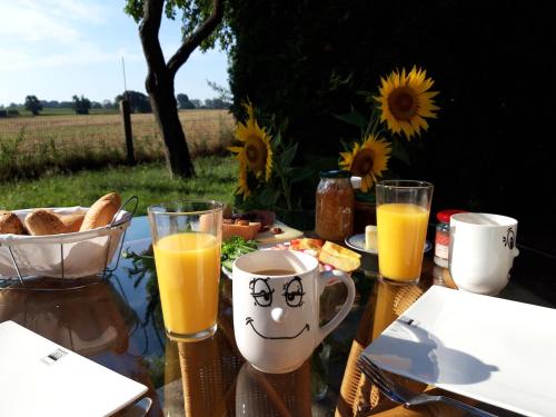 a table with glasses of orange juice and a plate of food at Ein Bett im Kornfeld - Haus Fernweh - Innenpool in Schönfeld