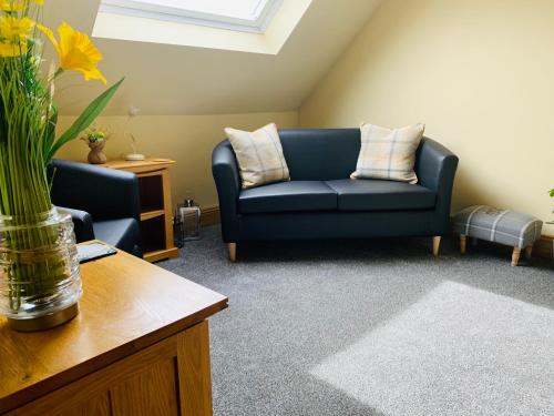 a living room with a blue couch and a table at Lakeview Guest House in Stranraer