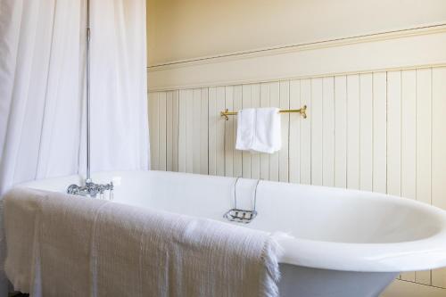 La salle de bains est pourvue d'une baignoire blanche et d'un lavabo. dans l'établissement Hôtel Château Albert, à Bertrand
