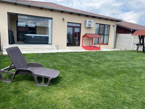 a chair sitting on a lawn in front of a house at Sia & Sophie House Oradea in Sîntandrei
