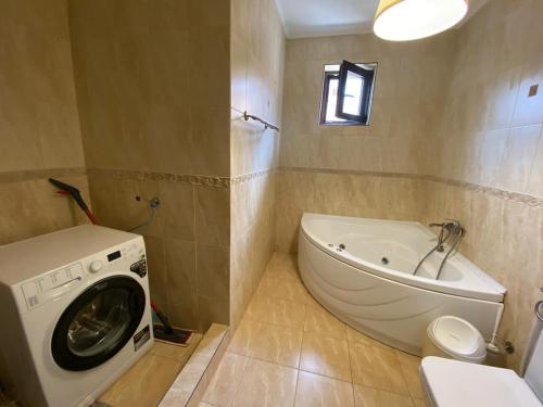 a bathroom with a washing machine and a tub at Sia & Sophie House Oradea in Sîntandrei