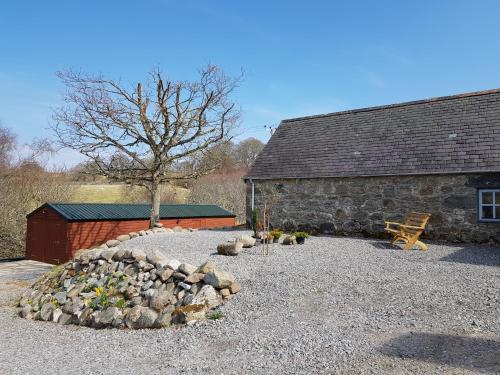 a stone building with a pile of rocks next to a tree at Jakels Rest in Lairg