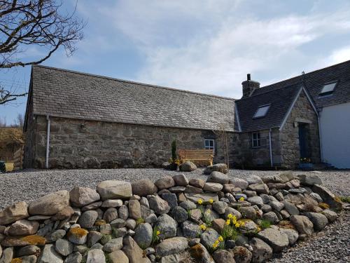 an old stone building with a rock wall in front of it at Jakels Rest in Lairg