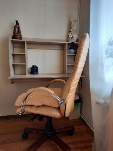 a brown chair in a room with shelves at Apartment in the historical city center in Chernivtsi