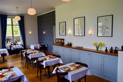 un restaurant avec des tables et des chaises blanches et un bar dans l'établissement Chambres d'Hôtes Le Clos des Marronniers, à Douvres-la-Délivrande