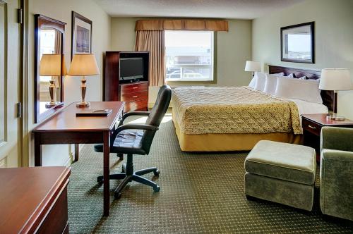 um quarto de hotel com uma cama, uma secretária e uma cadeira em Nova Inn Acheson em Spruce Grove