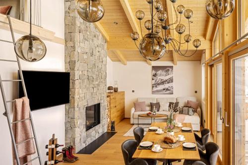 sala de estar con mesa, sillas y chimenea en Alpin Residenz Dachsteinperle, en Ramsau am Dachstein