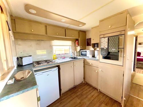 a large kitchen with white appliances and wooden floors at Poplar Lodge Log Caravan in Kirkby on Bain