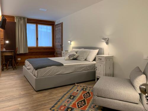a bedroom with a bed and a couch and a chair at lo Miete di Nonni in Champoluc