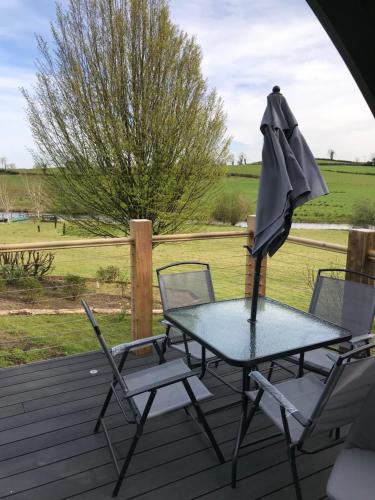 a table and chairs on a deck with an umbrella at Lough Erne Glamping Pod in Enniskillen