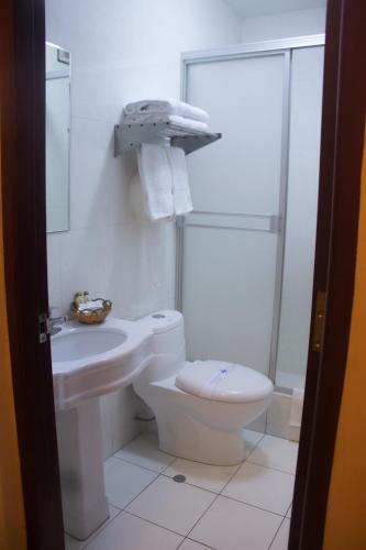 a white bathroom with a toilet and a sink at Royal Garden Hotel in Lima