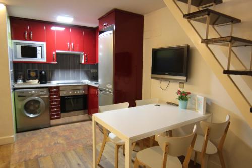 a kitchen with red cabinets and a white table and chairs at CHUECA Apartamentos Noxi in Madrid