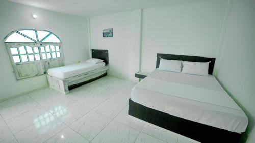 a white bedroom with a bed and a window at Hotel Kevins in Tolú