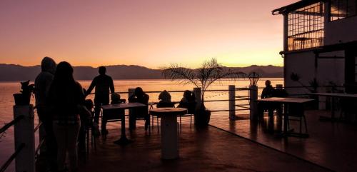 un grupo de personas sentadas en las mesas viendo la puesta de sol en Mikaso Hotel, en San Pedro La Laguna