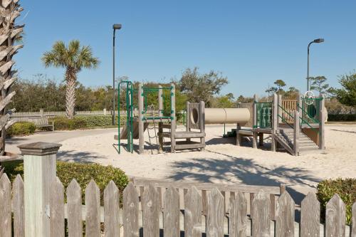a playground in a park with a wooden fence at The Beach Club Resort and Spa in Gulf Shores