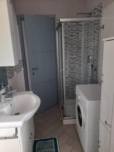 ein Badezimmer mit einem Waschbecken und einer Waschmaschine in der Unterkunft Appartamento al primo piano MARGHERITA in Sabaudia